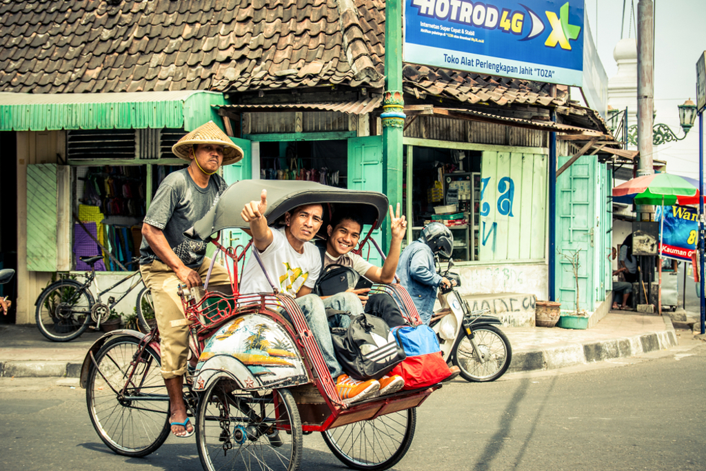 Becak met twee passagiers in een straat op Java, Indonesië, tijdens familiereis Sumatra, Java en Bali.