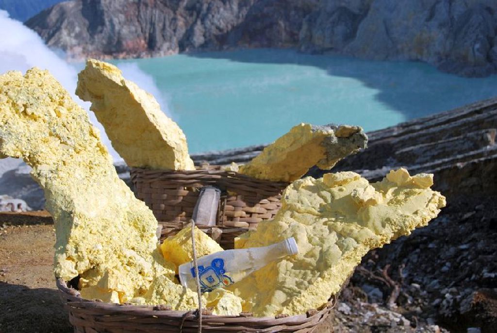 Zwavelwinning bij de Ijen-vulkaan met manden vol zwavel en kratermeer op Java, Indonesië.
