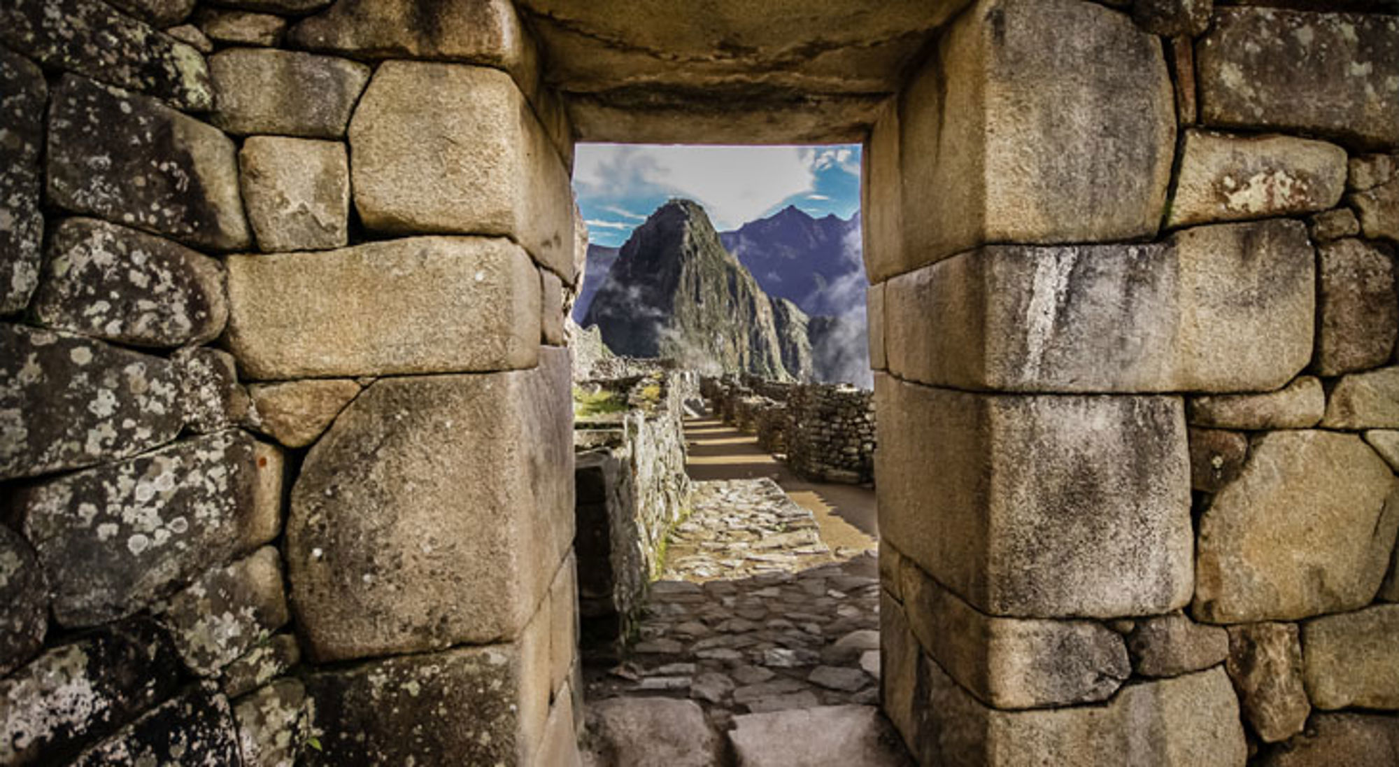 Deuropening Machu Picchu Doorkijk door stenen poort naar Machu Picchu met de Huayna Picchu-berg op de achtergrond, Peru.