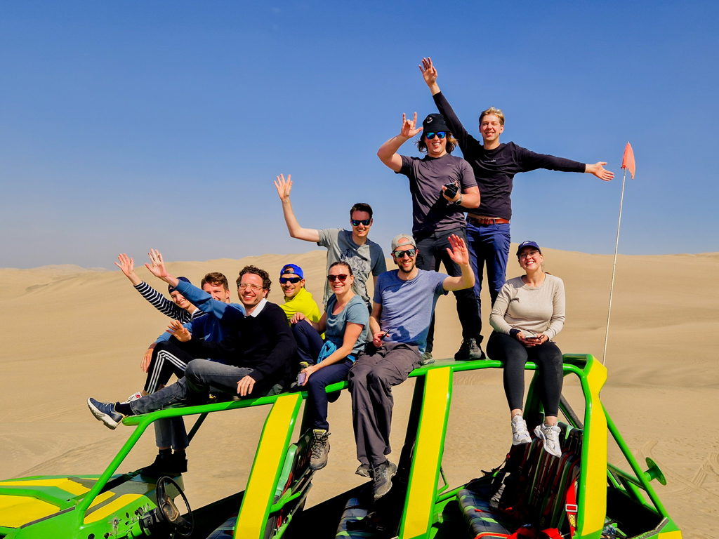 Groep 22-35ers op dune buggy in de woestijnduinen van Peru tijdens een groepsrondreis.