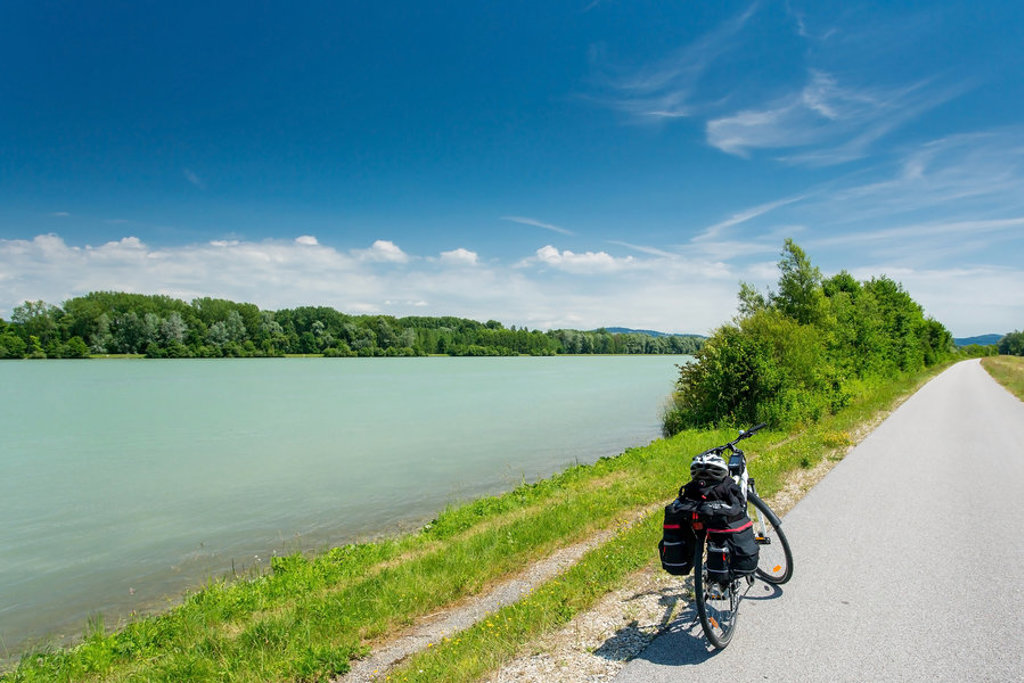 Fiets met fietstassen op het fietspad langs de Donau in Oostenrijk, met rivier en groene oevers.