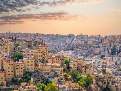 Panorama van Amman bij zonsondergang, met dichtbebouwde huizen op de heuvels van Jordanië.