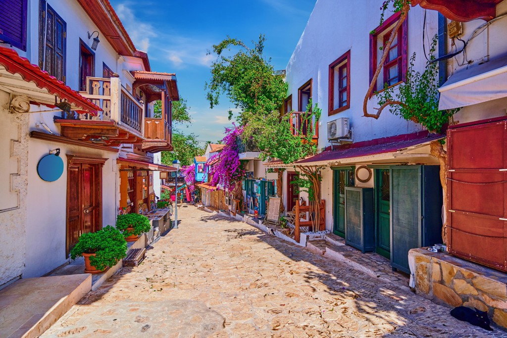 Sfeervol straatje aan de Turkse Turquoise Kust met witte huizen, houten balkons en bougainville.