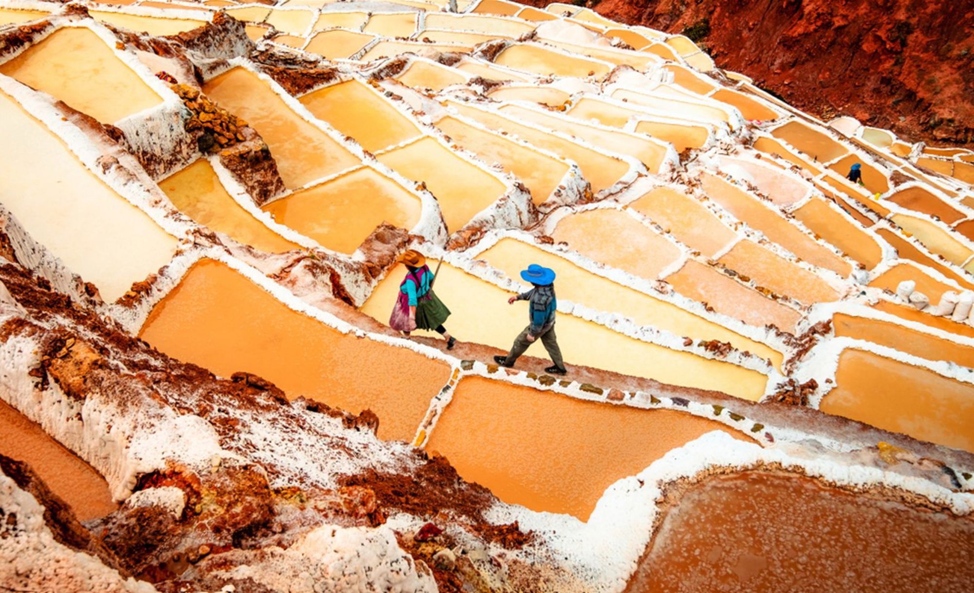 Zoutterrassen van Maras bij Cusco, Peru, met twee wandelaars tussen de zoutbassins.