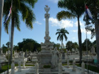Monument op een begraafplaats in Havana, omringd door palmbomen en Cubaanse vlaggen.