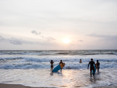 Surfers lopen met surfboards de zee in bij zonsondergang op Bali.