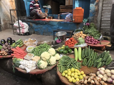 Groentekraam op een straatmarkt in India met tomaten, bloemkool, okra, komkommers en uien.