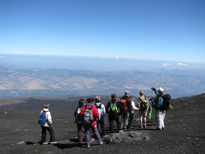 Wandelaars met rugzakken op de Etna met uitzicht over Sicilië tijdens de 8-daagse wandelvakantie.