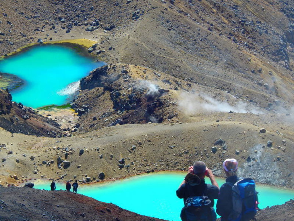 Wandelaars bij felblauwe kratermeren in het Tongariro National Park, Nieuw-Zeeland.