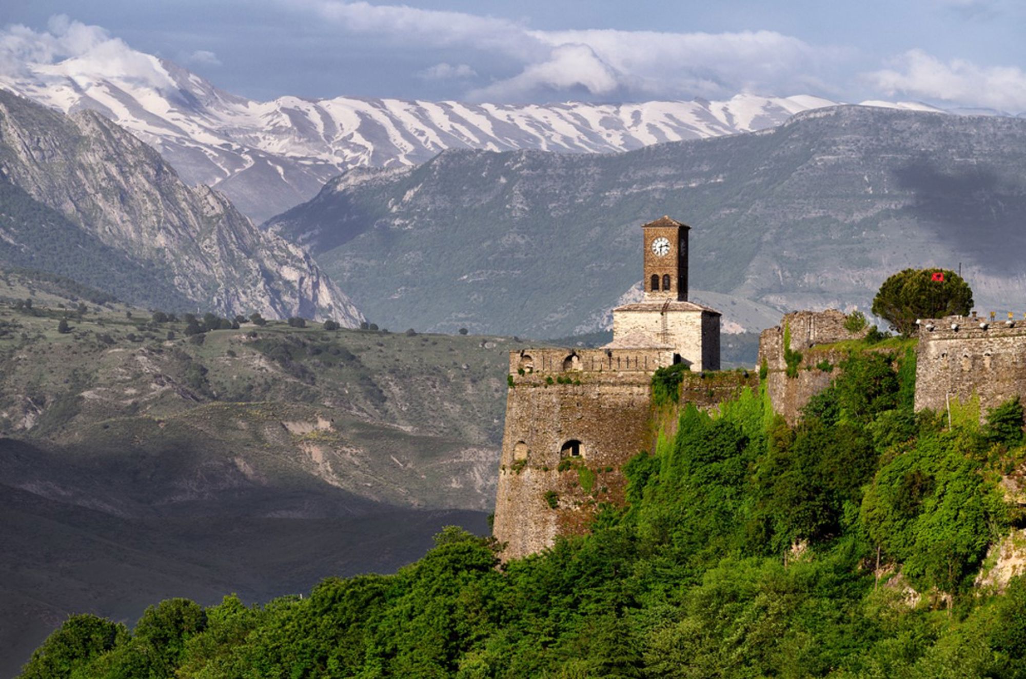 Kasteel van Gjirokastër met klokkentoren, met de besneeuwde bergen van Albanië op de achtergrond.