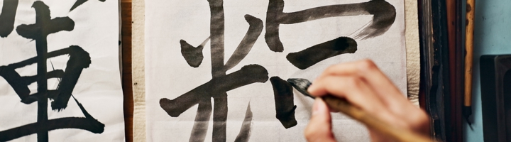 Hand schrijft kalligrafie met inkt op papier tijdens Sawadee Cultuurweken Week 4: Taal.