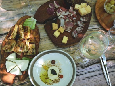 Balkan borrelplanken met kaas, vleeswaren, olijven en brood, geserveerd met witte wijn.