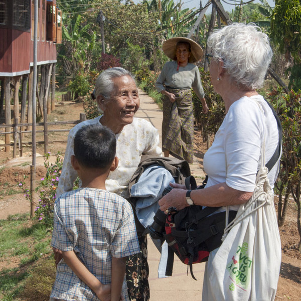 Reiziger praat met lokale bewoners in een dorp in Myanmar tijdens een groepsrondreis.