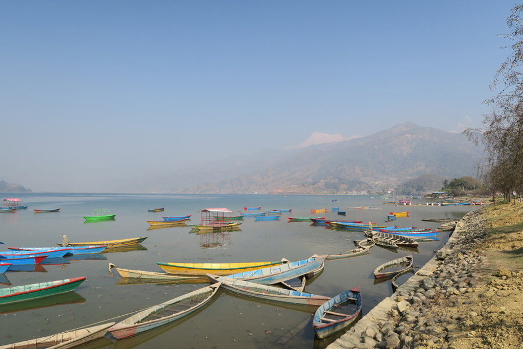 Kleurrijke bootjes op het Phewa-meer in Pokhara, met bergen op de achtergrond tijdens een groepsrondreis Noord-India en Nepal.