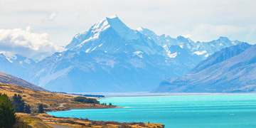 Panoramisch uitzicht op een turquoise meer met besneeuwde bergen op de achtergrond in Nieuw-Zeeland.
