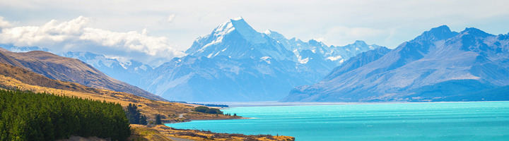 Panoramisch uitzicht op een turquoise meer met besneeuwde bergen op de achtergrond in Nieuw-Zeeland.