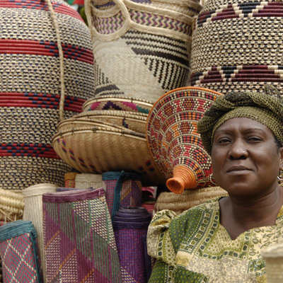 Vrouw op markt met kleurrijke gevlochten manden tijdens groepsrondreis Kenia en Tanzania.