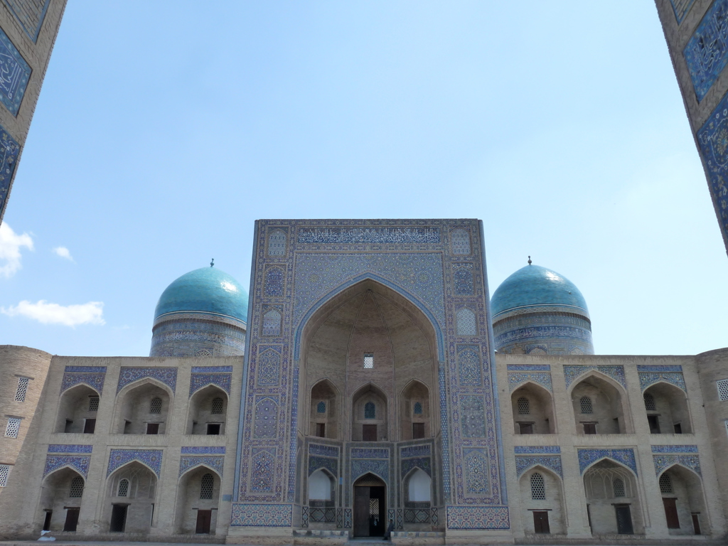 Gevel met blauwe koepels en mozaïektegels van een madrassa langs de Zijderoute.