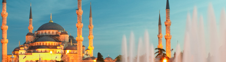 Blauwe Moskee in Istanbul bij zonsondergang, met verlichte minaretten en fontein op de voorgrond.