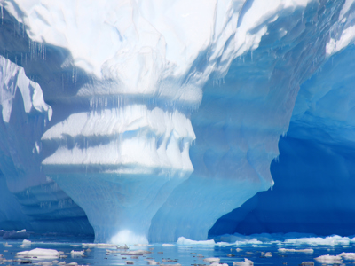 Gigantische blauwe ijsberg met ijsformaties en drijvende ijsschotsen in Antarctica.