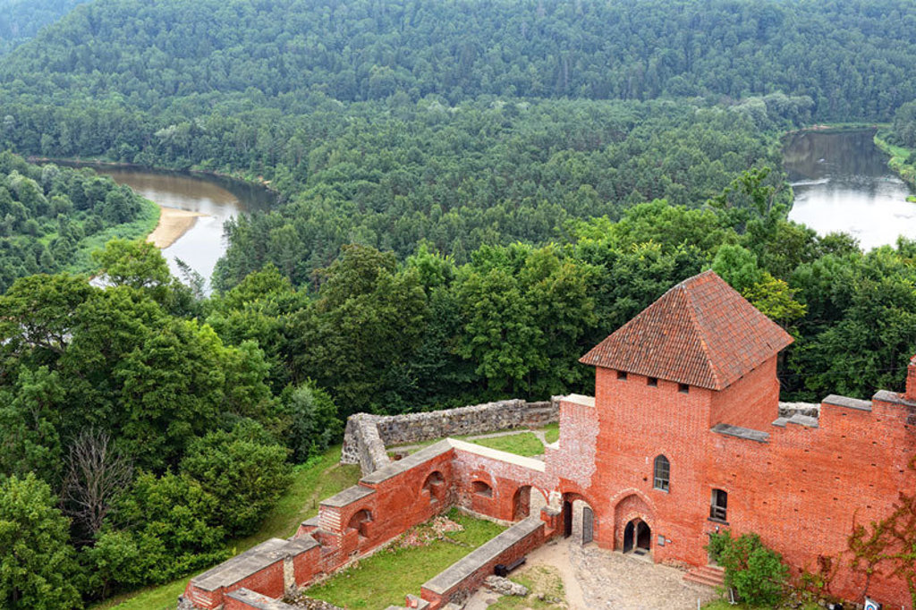 Uitzicht vanaf kasteelruïne op de Gauja-rivier en groene bossen in Letland tijdens een groepsrondreis.