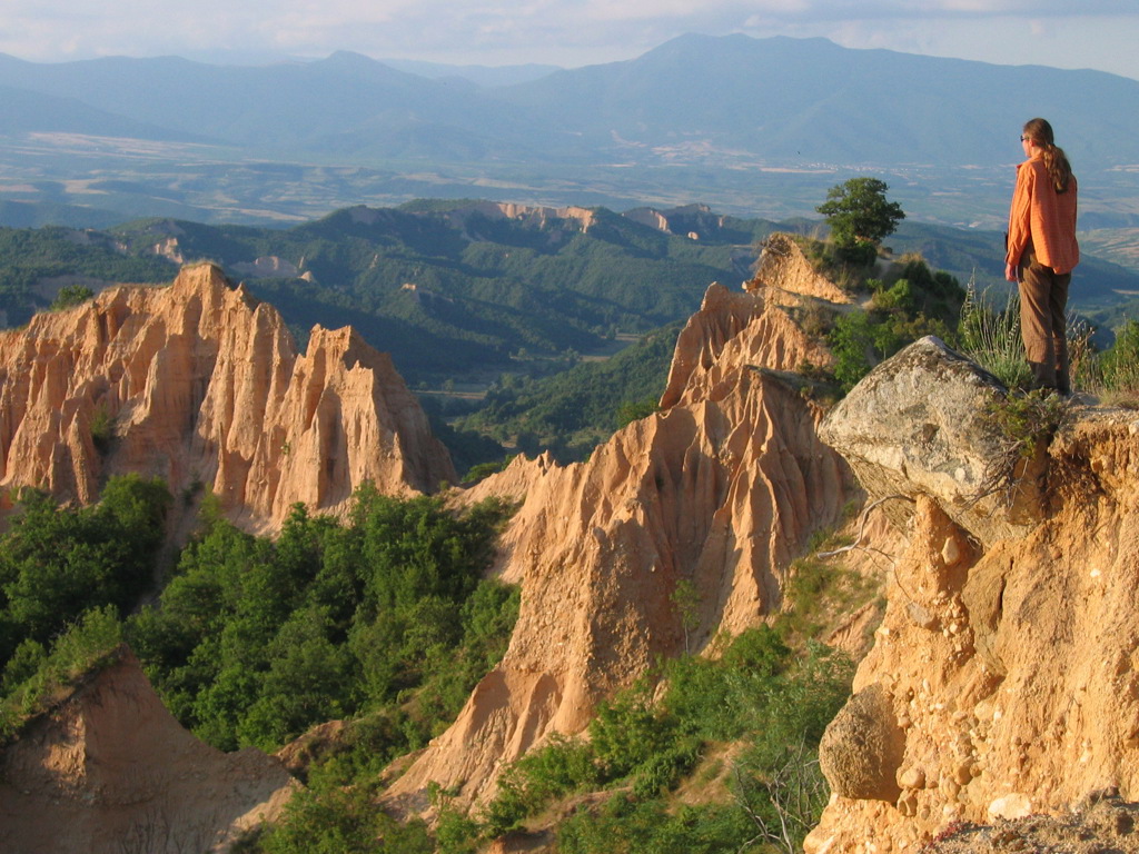 Wandelvakantie Bulgarije: wandelaar kijkt uit over rotsformaties en groene valleien in de Bulgaarse Balkan.
