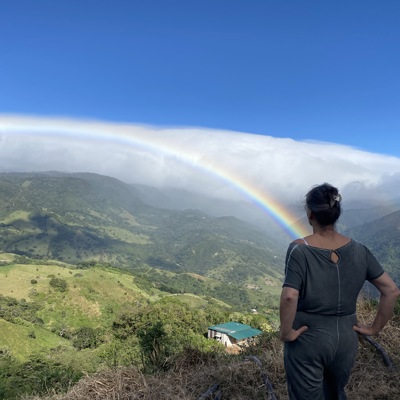 Reiziger kijkt uit over groene bergen langs de Pan-American Highway in Guatemala, met een regenboog aan de hemel.