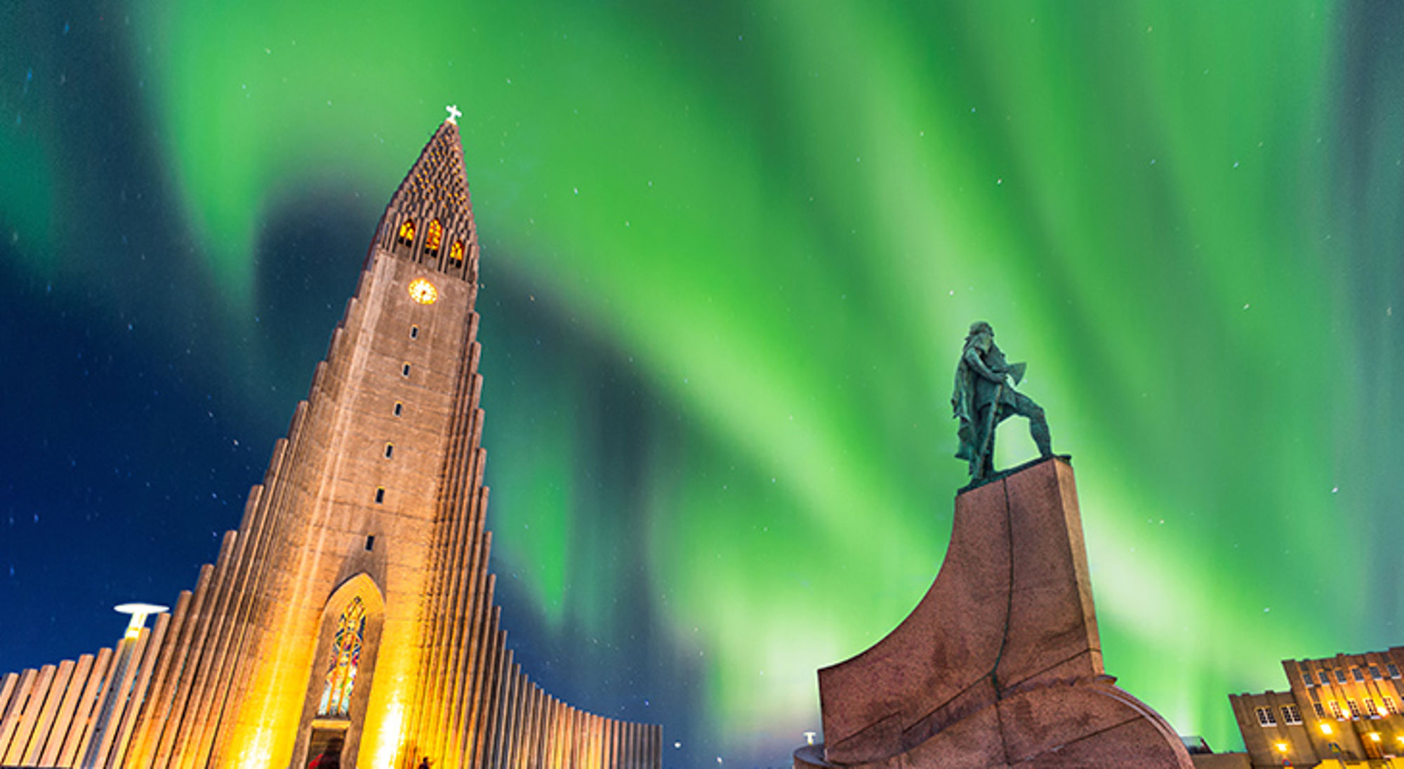 reykjavik-ijsland-noorderlicht Noorderlicht boven Hallgrímskirkja en een standbeeld in Reykjavik, IJsland.