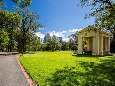 Park in Melbourne met wandelpad, gazebo en skyline op de achtergrond.