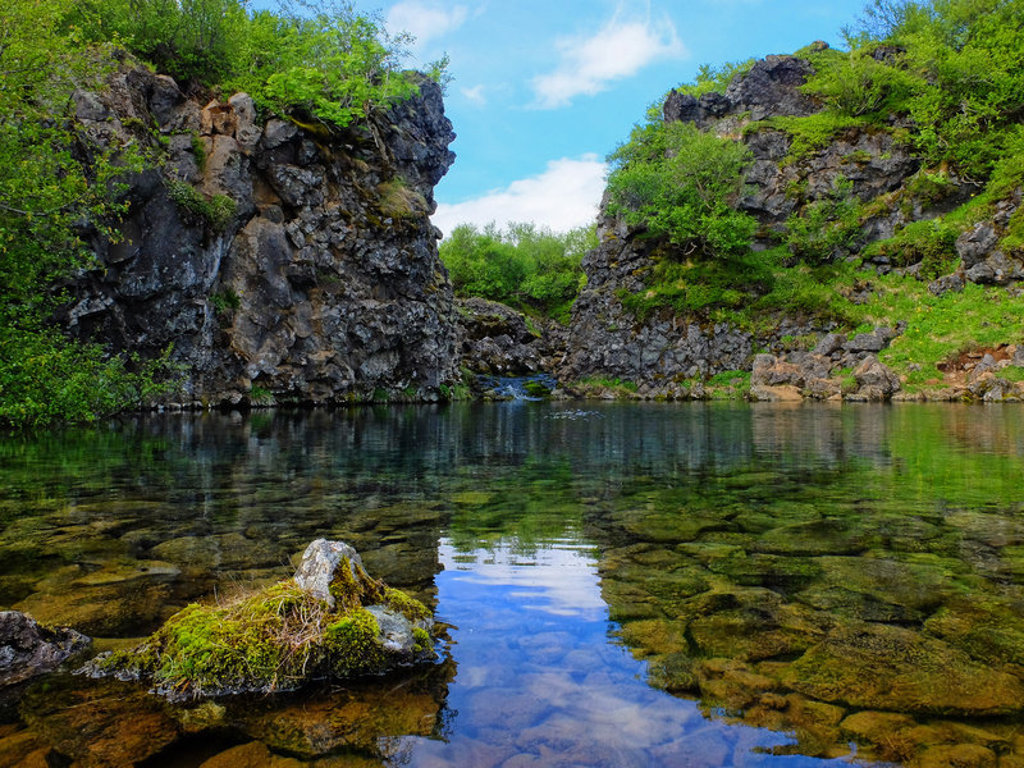 Groene kloof met helder water en rotswanden in IJsland, tijdens een groepsrondreis kamperen.