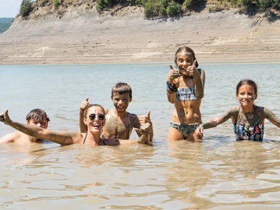 Kinderen en begeleider zwemmen in een meer in Aragon bij de Rio Cinca, Spanje.