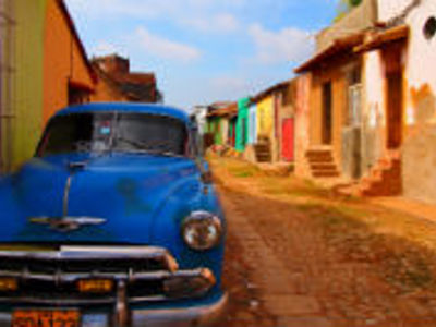 Blauwe klassieke auto in een kleurrijke straat in Cuba, onderdeel van de reisroute Cuba 23 dagen.