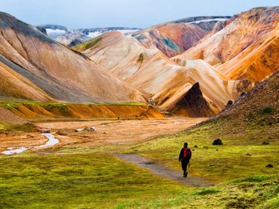 Wandelaar in Landmannalaugar met kleurrijke rhyolietbergen en lavaveld in IJsland.