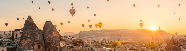 Zonsopgang boven Göreme met tientallen luchtballonnen en rotsformaties in Cappadocië, Turkije.