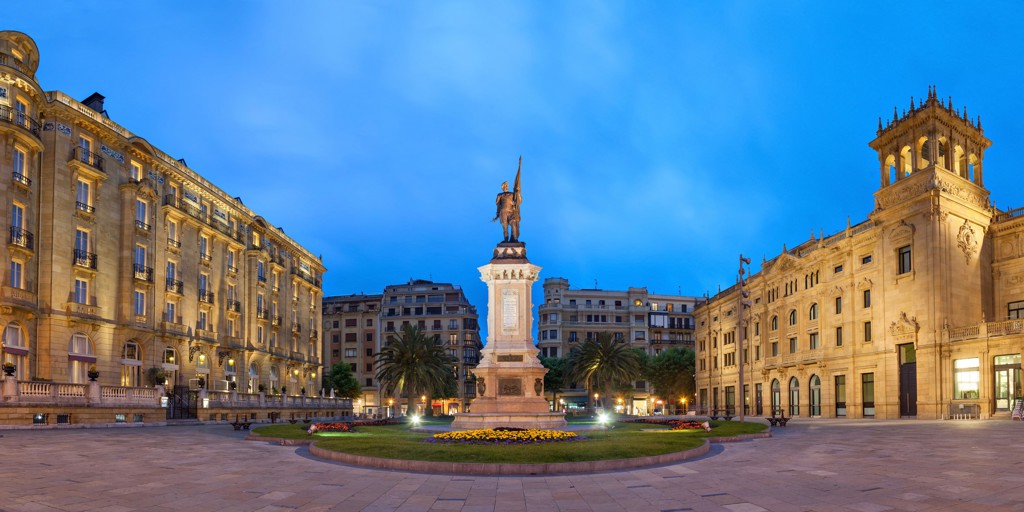Verlicht plein met standbeeld en historische gebouwen in San Sebastián tijdens een familiereis Spanje & Portugal.