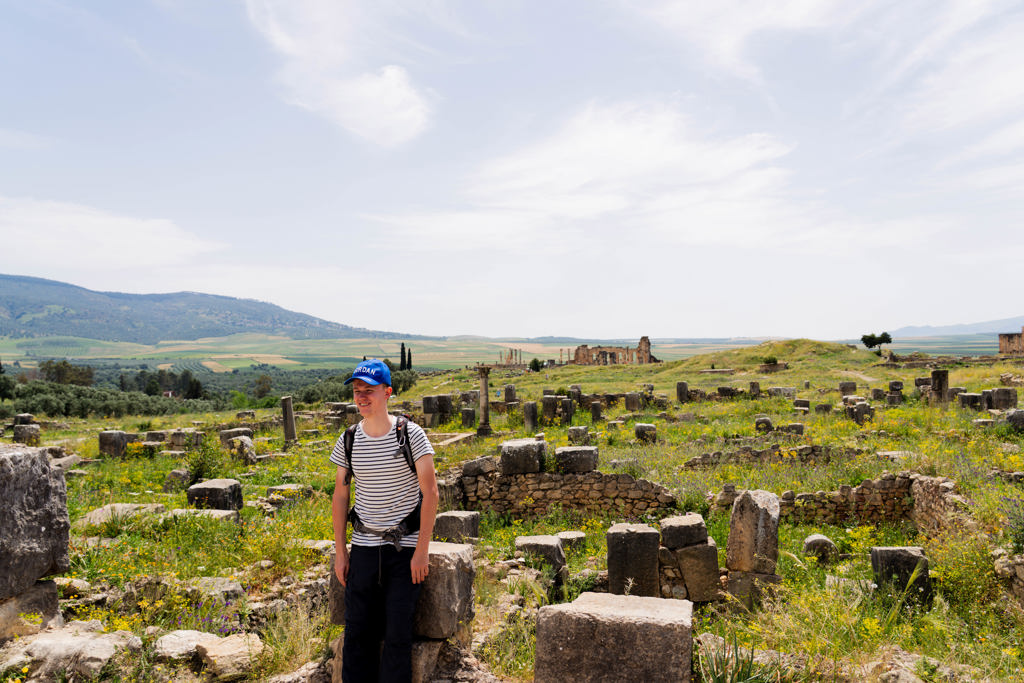 Jonge reiziger verkent Romeinse ruïnes in Volubilis tijdens een 22-35ers reis door Marokko.