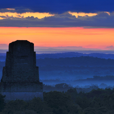 Zonsopkomst bij een Maya-tempel boven de jungle in Guatemala.