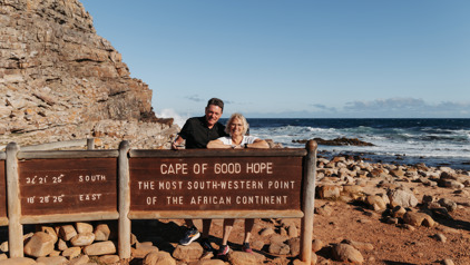 Reizigers bij het bord van Kaap de Goede Hoop, Zuid-Afrika, met rotskust en oceaan op de achtergrond.
