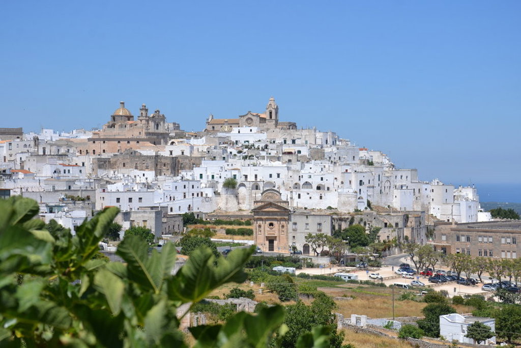 Witte huizen en kerken in Ostuni, Puglia, met uitzicht op het landschap tijdens een wandelvakantie in Italië.