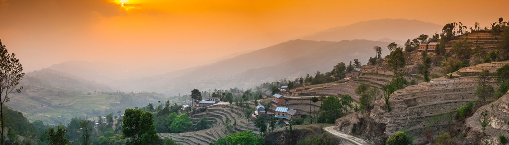 Zonsondergang boven rijstterrassen en heuveldorp in Nepal tijdens een familiereis.
