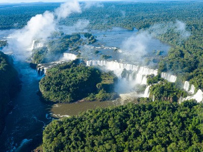 Panoramisch uitzicht op de Iguazú-watervallen, omringd door dicht regenwoud en nevel.
