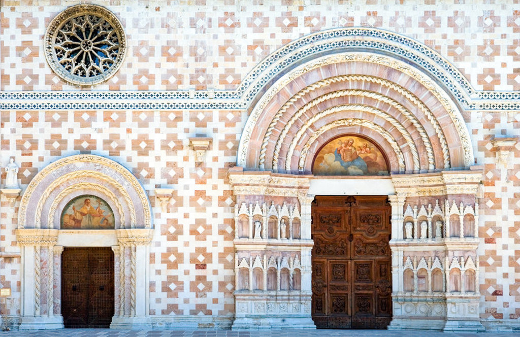 Romaanse kerkgevel met rijk versierde bogen en houten deuren in de Centrale Apennijnen, Italië.