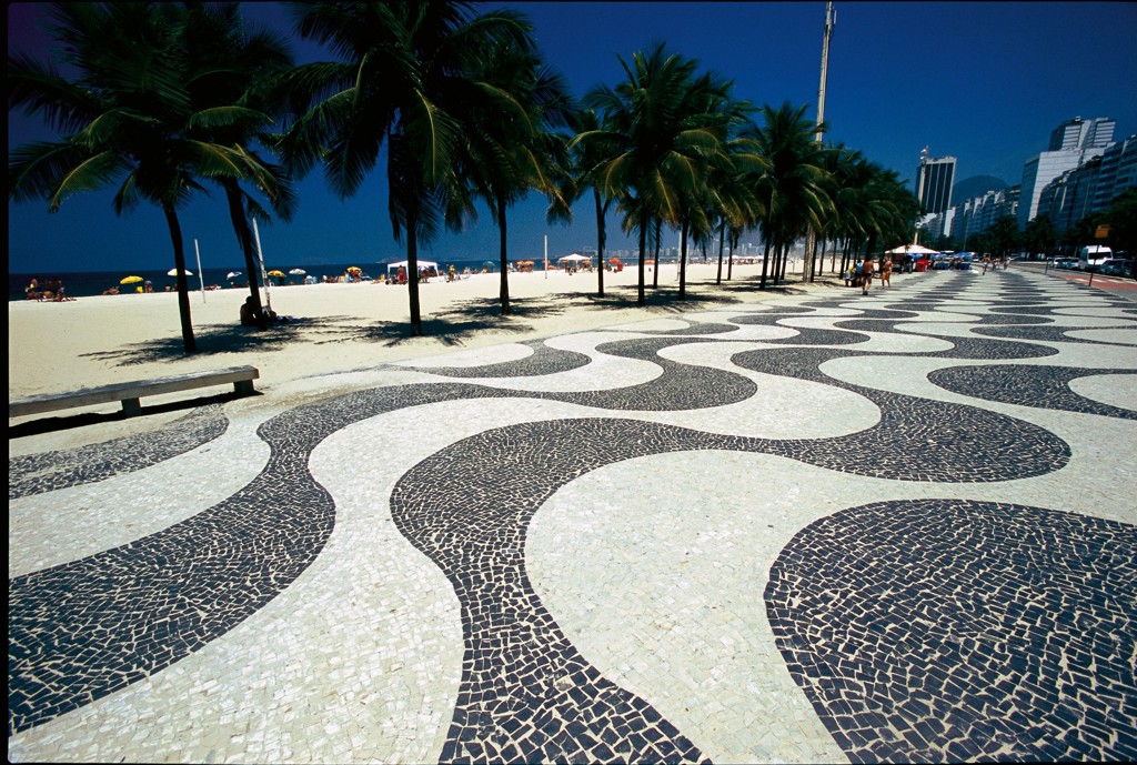 Golvend mozaïek op de boulevard van Copacabana met palmbomen en strand in Rio de Janeiro, Brazilië.