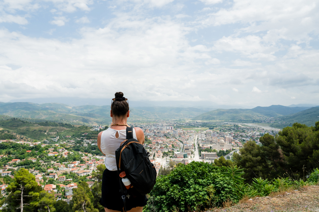 Wandelaar met rugzak kijkt uit over de stad Tirana en omliggende bergen in Albanië.