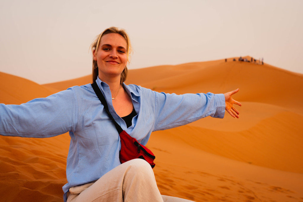 Reiziger in de Sahara in Marokko met uitgestrekte zandduinen tijdens een 22-35ers groepsrondreis.
