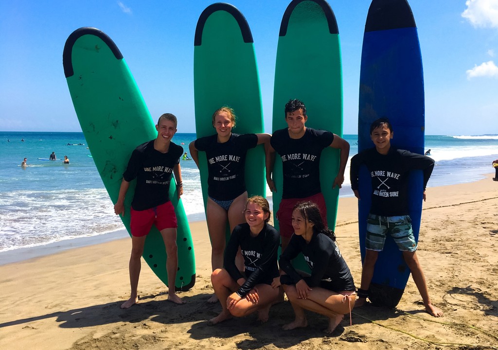 Surfers met surfplanken op het strand van Bali tijdens familiereis Sulawesi & Bali.