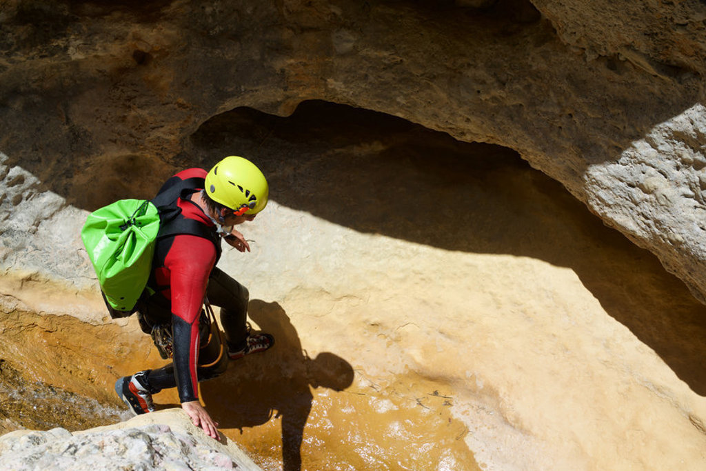Canyoning in Slovenië tijdens 22-35ers groepsrondreis, met helm en wetsuit in een rotsachtige kloof.