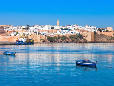 Uitzicht op Rabat aan de Atlantische kust met vissersbootjes op zee en de kasbah op de achtergrond.
