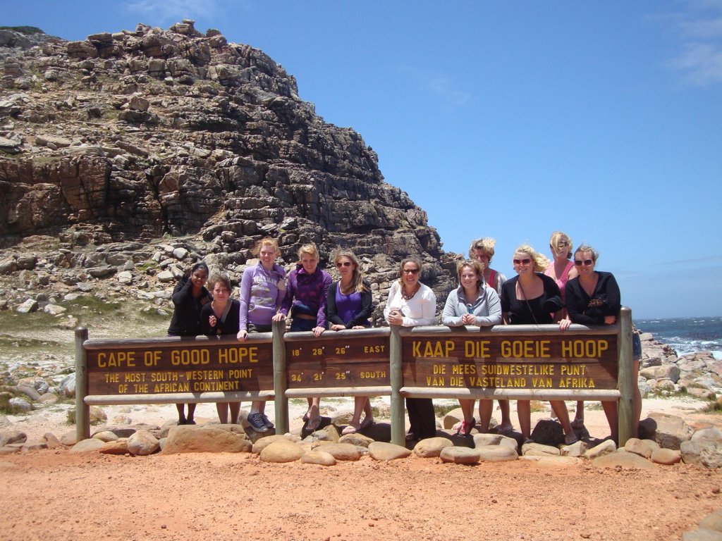 Groepsfoto bij het bord van Kaap de Goede Hoop tijdens familiereis Zuid-Afrika Tuinroute & Kruger.