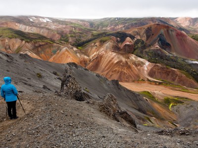 Wandelaar kijkt uit over de kleurrijke rhyolietbergen van Landmannalaugar tijdens de 7-daagse wandelvakantie IJsland.